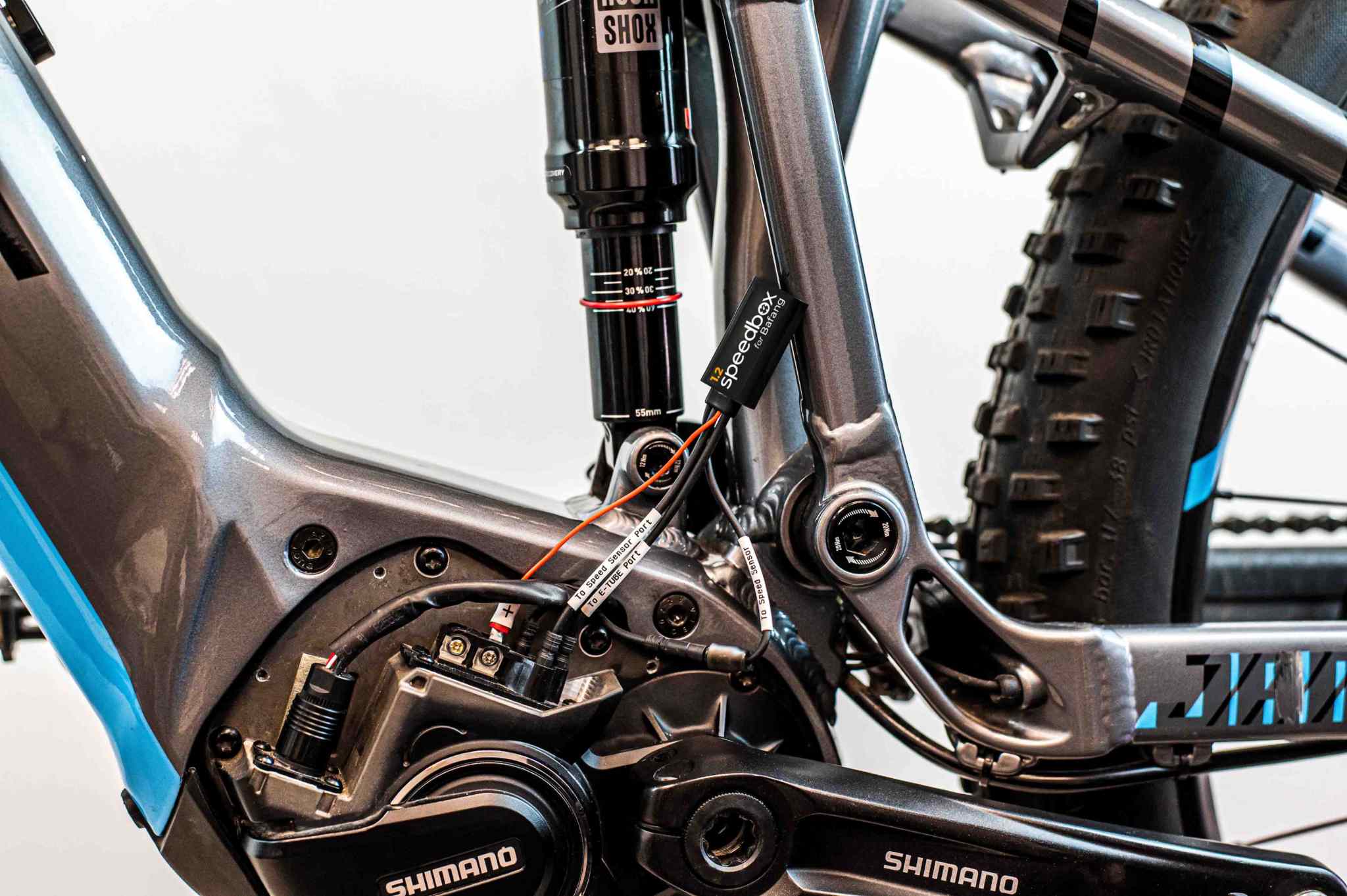 SpeedBox 1.2 tuning module installed on Shimano E8000 e-bike motor with wiring and frame components visible